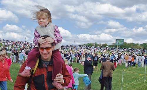 photo: happy father carrying happy daughter through a crowd of people outdoors