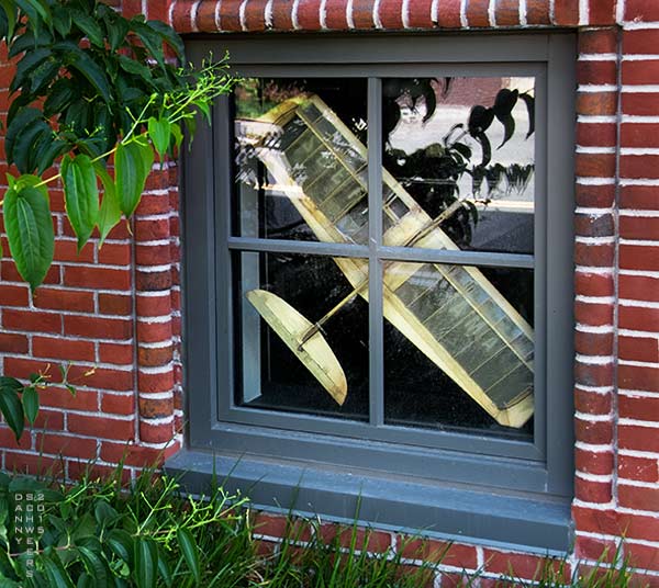 Balsa wood airplane trapped behind a window.