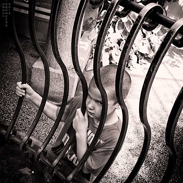 Boy behind bars watching girls, photo by Danny N. Schweers.