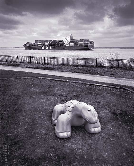 Photo of a playscape brontosaurus and the container ship MOL Glide at Fox Point State Park, Delaware, copyright 2021 by Danny N. Schweers.