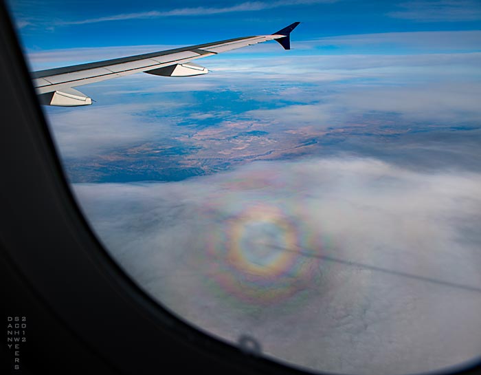 Photo of concentric rainbows — a ‘glory’ — centered on an airliner’s shadow, copyright 2012 by Danny N. Schweers.